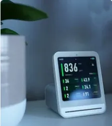 Smart air quality monitor display on a desk showing real-time environmental data and indoor climate metrics.